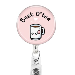 Puede incluir: Un carrete de credencial rosa con una taza blanca con una cara sonriente y una bolsita de té. La taza tiene líquido marrón en su interior y sale vapor de ella. El texto en el carrete de credencial dice "Best O'tea".