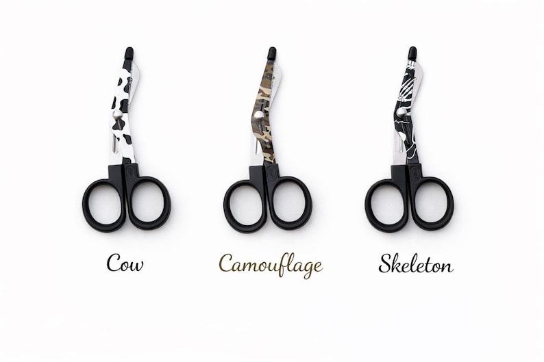 May include: Three pairs of black-handled scissors with decorative blades. Designs include a cow print, camouflage pattern, and a skeleton motif. The word "Cow", "Camouflage", and "Skeleton" are written below each pair of scissors.