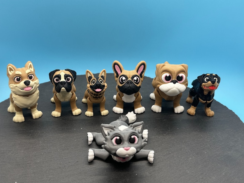 May include: A collection of seven small, cartoon-style animal figurines. The figurines are made of a brown, tan, and black plastic. The figurines include a dog, a cat, a bulldog, a rottweiler, a corgi, a french bulldog, and a german shepherd.