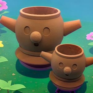 May include: Two brown ceramic pots with a cartoon-like face, arms, and a round base. The pots are of different sizes, with the larger one in the background and the smaller one in the foreground. The background features green grass and colorful flowers.