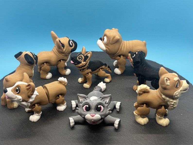 May include: A set of eight articulated animal figurines, including a cat, a corgi, a bulldog, a french bulldog, a german shepherd, a chihuahua, a husky, and a shiba inu. The figurines are made of brown, black, and gray plastic and have movable limbs.