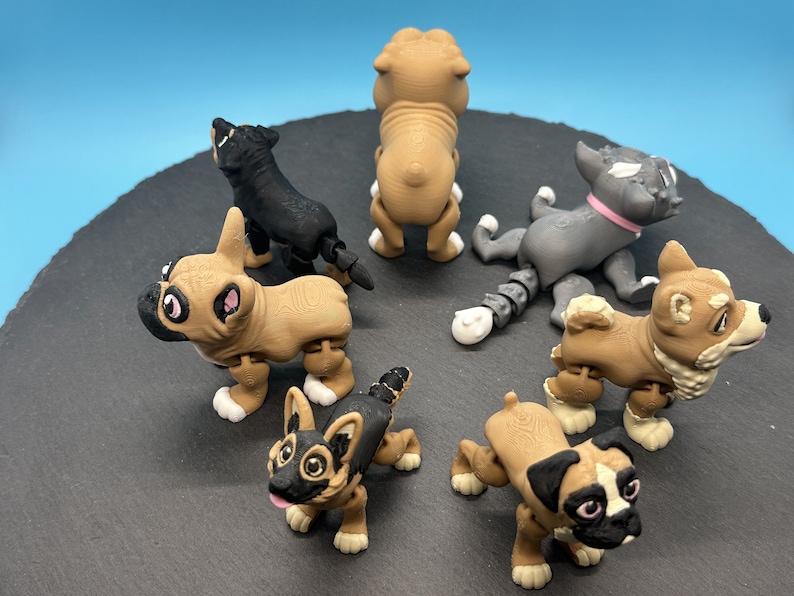 May include: Six small, articulated, plastic dog figurines. The dogs are in various poses and are made of brown, black, and gray plastic. The figurines are on a black surface.