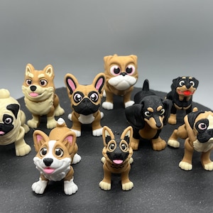 May include: A collection of nine small, hand-painted figurines of different dog breeds. The figurines are made of a brown and black material and have realistic features. The dogs include a pug, a corgi, a dachshund, a bulldog, a German Shepherd, a French Bulldog, a Rottweiler, and two other breeds.