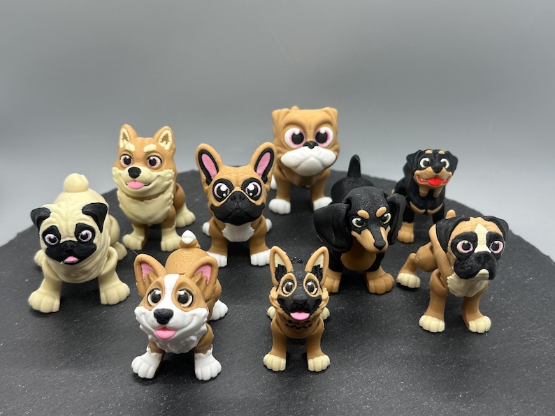 May include: A collection of nine small, hand-painted figurines of different dog breeds. The figurines are made of a brown and black material and have realistic features. The dogs include a pug, a corgi, a dachshund, a bulldog, a German Shepherd, a French Bulldog, a Rottweiler, and two other breeds.