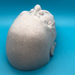 May include: A white 3D printed sculpture of a human head with a textured surface.