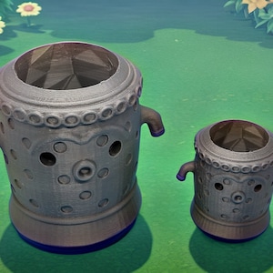 May include: Two gray decorative urns with a textured surface and a detailed design. The urns have a cylindrical shape with a wide opening at the top, small handles, and a blue base. The urns are of different sizes.