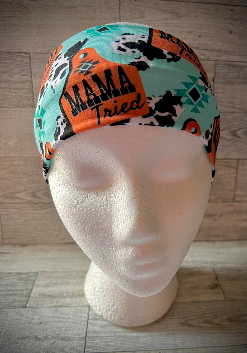 May include: A turquoise, orange, and black headband with a cow print and the text "Mama Tried".