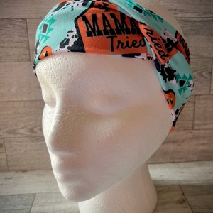 May include: A turquoise, orange, and black patterned headband with the text "Mama Tried" printed on it.