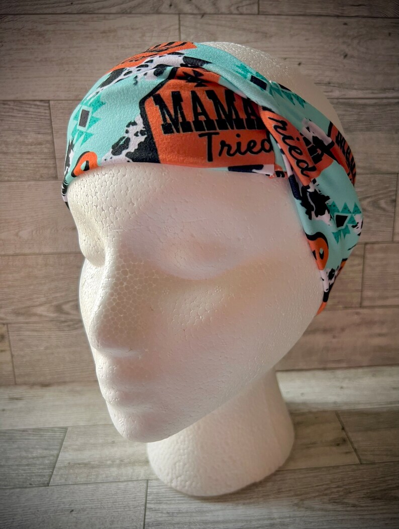 May include: A turquoise, orange, and black patterned headband with the text "Mama Tried" printed on it.