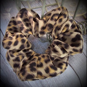 May include: A brown and black leopard print scrunchie hair tie.