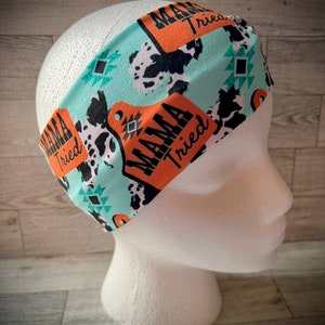 May include: Turquoise headband with a cow print and orange "Mama Tried" text.