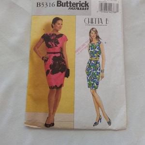 May include: A sewing pattern for a dress, Butterick pattern B5316, with two different styles. The first style is a pink dress with black floral print and a black belt. The second style is a blue and green dress with a yellow belt. The pattern is for sizes 6-8-10-12.