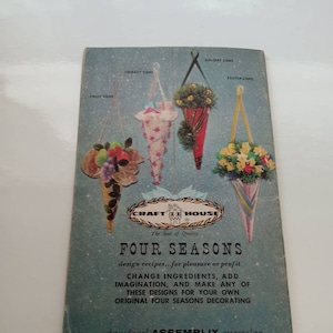 Könnte beinhalten: Ein Vintage-Bastelheft mit blauem Hintergrund und dem Titel "Four Seasons" in weißer Schrift. Das Heft zeigt vier kegelförmige Dekorationen, die jeweils eine andere Jahreszeit repräsentieren: Obst, Schmuck, Feiertage und Ostern. Das Heft stammt von der Firma "Craft House" und ist zum Basteln von Dekorationen gedacht.