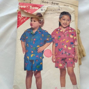 May include: A vintage sewing pattern for children's clothing. The pattern is for a short-sleeved shirt and shorts set with a tropical print. The pattern is from See & Sew and is size B (5).