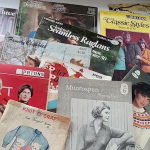Puede incluir: Una colección de libros de patrones de tejido de punto vintage con portadas coloridas que presentan varios proyectos de tejido de punto, incluidos suéteres, mantas y sombreros. Las portadas presentan títulos como "Beehive", "Seamless Raglans", "Classic Styles" y "Knitting in the Round".
