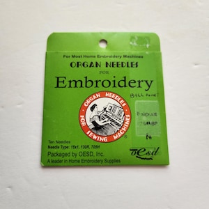May include: A green packet of Organ Needles for embroidery machines. The packet features the text "Embroidery" and "Organ Needles" in white. A circular logo shows a person using a sewing machine. The packet contains ten needles.
