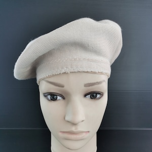 Puede incluir: Boina beige de tejido de punto acanalado. La boina se exhibe en una cabeza de maniqu&iacute;. La boina tiene forma circular y una banda alrededor de la base. La boina es de color neutro.