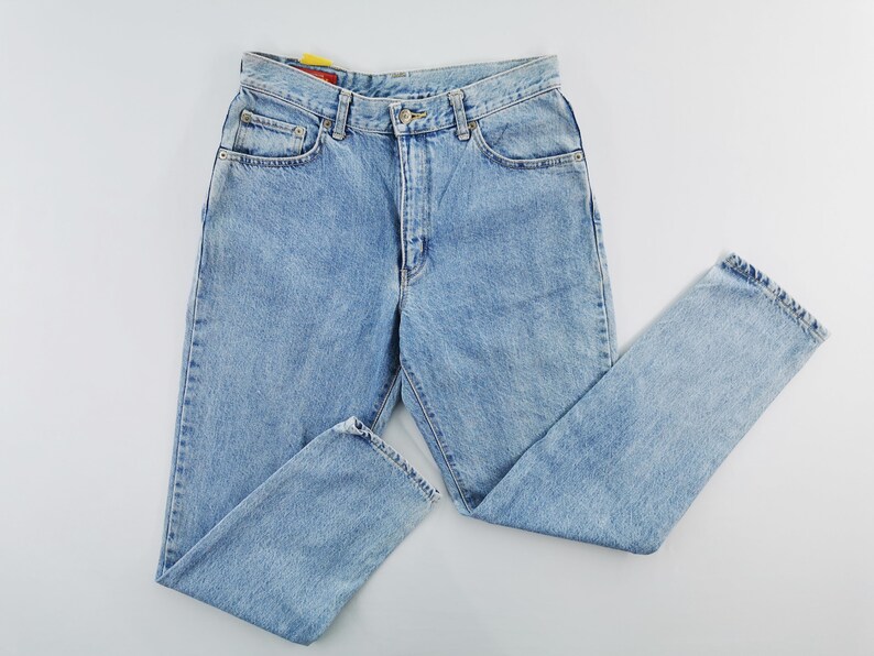 May include: Light blue denim jeans with a classic five-pocket design. The jeans have a button and zipper closure, belt loops, and a straight leg cut. The denim appears to be a medium weight, suitable for everyday wear.