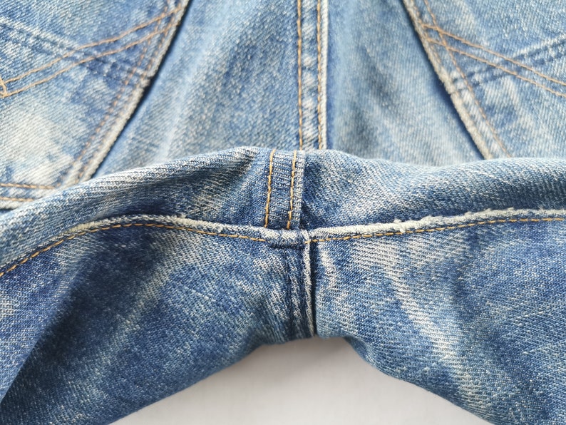 K&ouml;nnte beinhalten: Nahaufnahme einer hellblauen Jeans. Das Bild zeigt den Schrittbereich mit sichtbaren N&auml;hten und abgenutzten Details. Der Denim hat ein verblasstes, abgenutztes Aussehen.