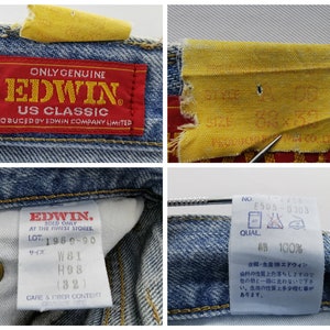 May include: Close-up of blue denim jeans with multiple tags. One tag reads "ONLY GENUINE EDWIN US CLASSIC." Another tag shows size W81, H98 (32). A third tag indicates the jeans are 100% cotton.