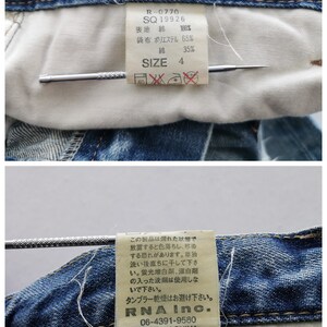 May include: Close-up of the inside of blue denim jeans. The jeans have a white interior with tags displaying size 4, fabric composition, and washing instructions. Additional tag includes "RNA Inc." and "MADE IN CHINA".