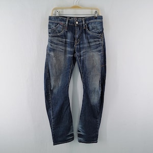 May include: Dark blue denim jeans with a faded effect and subtle wear. The jeans are hanging on a wooden hanger against a white background. Features include a button closure, pockets, and belt loops.