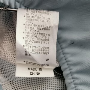 May include: A close-up of a clothing tag with Japanese text, a white mesh fabric, and a light blue fabric. The tag reads "MADE IN CHINA".