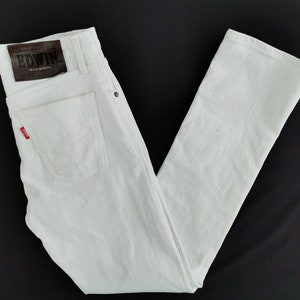 K&ouml;nnte beinhalten: Wei&szlig;e Jeans aus Denim mit klassischem F&uuml;nf-Taschen-Design. Verf&uuml;gt &uuml;ber einen braunen Lederaufn&auml;her mit dem "EDWIN"-Logo und ein rotes Etikett auf der Ges&auml;&szlig;tasche. Die Jeans werden in Japan hergestellt.