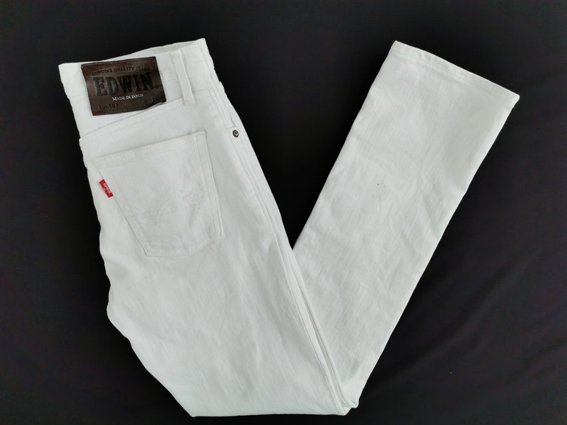 K&ouml;nnte beinhalten: Wei&szlig;e Jeans aus Denim mit klassischem F&uuml;nf-Taschen-Design. Verf&uuml;gt &uuml;ber einen braunen Lederaufn&auml;her mit dem "EDWIN"-Logo und ein rotes Etikett auf der Ges&auml;&szlig;tasche. Die Jeans werden in Japan hergestellt.