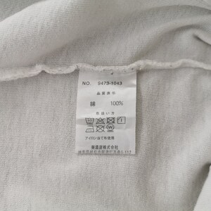 Peut inclure: Gros plan sur un tissu blanc avec une &eacute;tiquette attach&eacute;e. L'&eacute;tiquette affiche le num&eacute;ro "9473-1043" et du texte japonais indiquant que le mat&eacute;riau est 100% coton. Des instructions de lavage sont &eacute;galement affich&eacute;es.