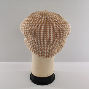 Puede incluir: Gorra de estilo newsboy con estampado marr&oacute;n y blanco. El sombrero est&aacute; hecho de un material tejido y tiene una corona redondeada y una peque&ntilde;a visera. La gorra se exhibe sobre una cabeza de maniqu&iacute; sobre un fondo blanco.