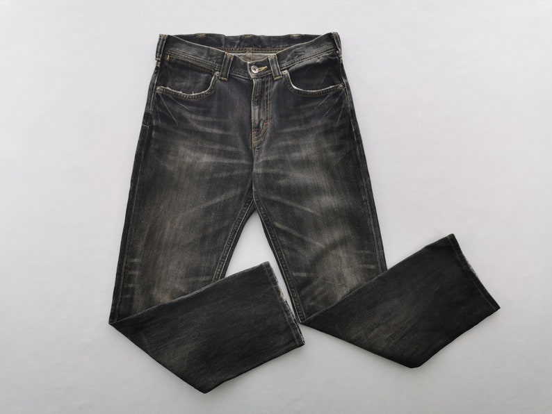 May include: Dark gray denim jeans with a faded wash. The jeans have a classic five-pocket design, a button and zipper closure, and a straight leg. The fabric appears worn and distressed.