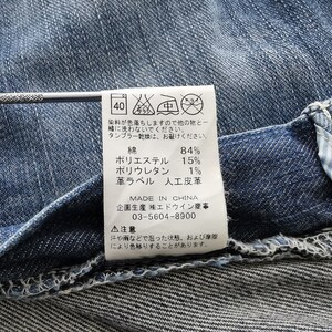 May include: Close-up of blue denim fabric with a sewn-in label. The label provides washing instructions and fabric composition: 84% cotton, 15% polyester, and 1% polyurethane. The label also indicates the product was made in China.