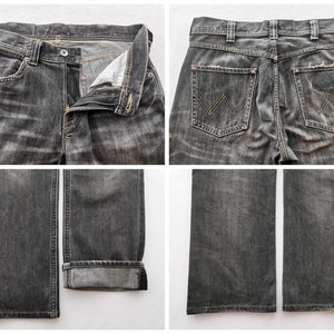 May include: Close-up shots of a pair of black denim jeans. The jeans have a button and zipper closure, front and back pockets, and the Wrangler logo on the back pockets. The jeans are distressed with faded areas.