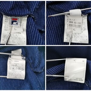 Puede incluir: Una prenda de color azul oscuro con rayas finas y etiquetas blancas de cuidado y talla en el interior. Las etiquetas muestran el logotipo de Fila, la talla L y texto en japon&eacute;s que indica un pecho de 92-100 cm y una altura de 170-180 cm.