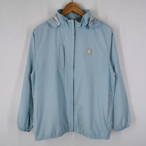 May include: A light blue hooded jacket with a full zipper closure. The jacket has a small square logo on the chest and a zippered pocket on the left side. The jacket is hanging on a wooden hanger.