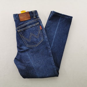 May include: Dark blue denim jeans with a classic five-pocket design. Features a brown leather patch with embossed text and a distinctive W-shaped stitching on the back pockets. The jeans have a straight leg cut and a small red tag.