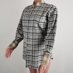 May include: A gray plaid long-sleeve shirt with a mandarin collar and button-down front. The cuffs and collar feature a contrasting plaid pattern in shades of green, brown, and beige. The shirt has a relaxed fit and is displayed on a mannequin.