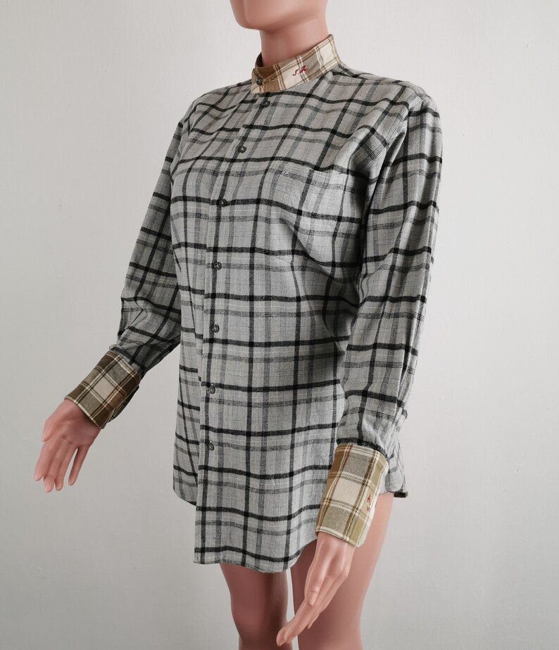 May include: A gray plaid long-sleeve shirt with a mandarin collar and button-down front. The cuffs and collar feature a contrasting plaid pattern in shades of green, brown, and beige. The shirt has a relaxed fit and is displayed on a mannequin.