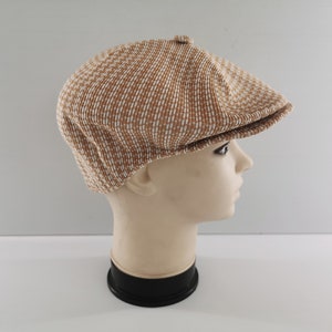 Puede incluir: Gorra de estilo newsboy con estampado marr&oacute;n y blanco. La gorra se muestra en una cabeza de maniqu&iacute;. Tiene una corona redondeada y una visera corta y r&iacute;gida. La tela tiene un aspecto texturizado.