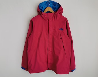 Puede incluir: Una chaqueta con capucha de color magenta que presenta un forro interior azul brillante, un cierre de cremallera frontal con solapa protectora y un pequeño logotipo azul bordado en el pecho izquierdo. Incluye mangas largas con puños ajustables.