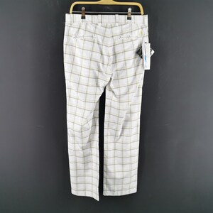 Op de afbeelding: Witte geblokte broek met een geel en bruin ruitpatroon. De broek heeft een riemlusband en een rits.