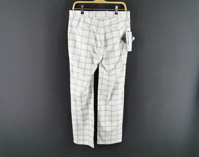 Op de afbeelding: Witte geblokte broek met een geel en bruin ruitpatroon. De broek heeft een riemlusband en een rits.