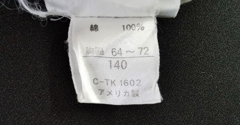 May include: A white fabric tag with Japanese characters, the number 100%, and the measurements 64-72 and 140. The tag also includes the text "C-TK 1602" and "Made in America."