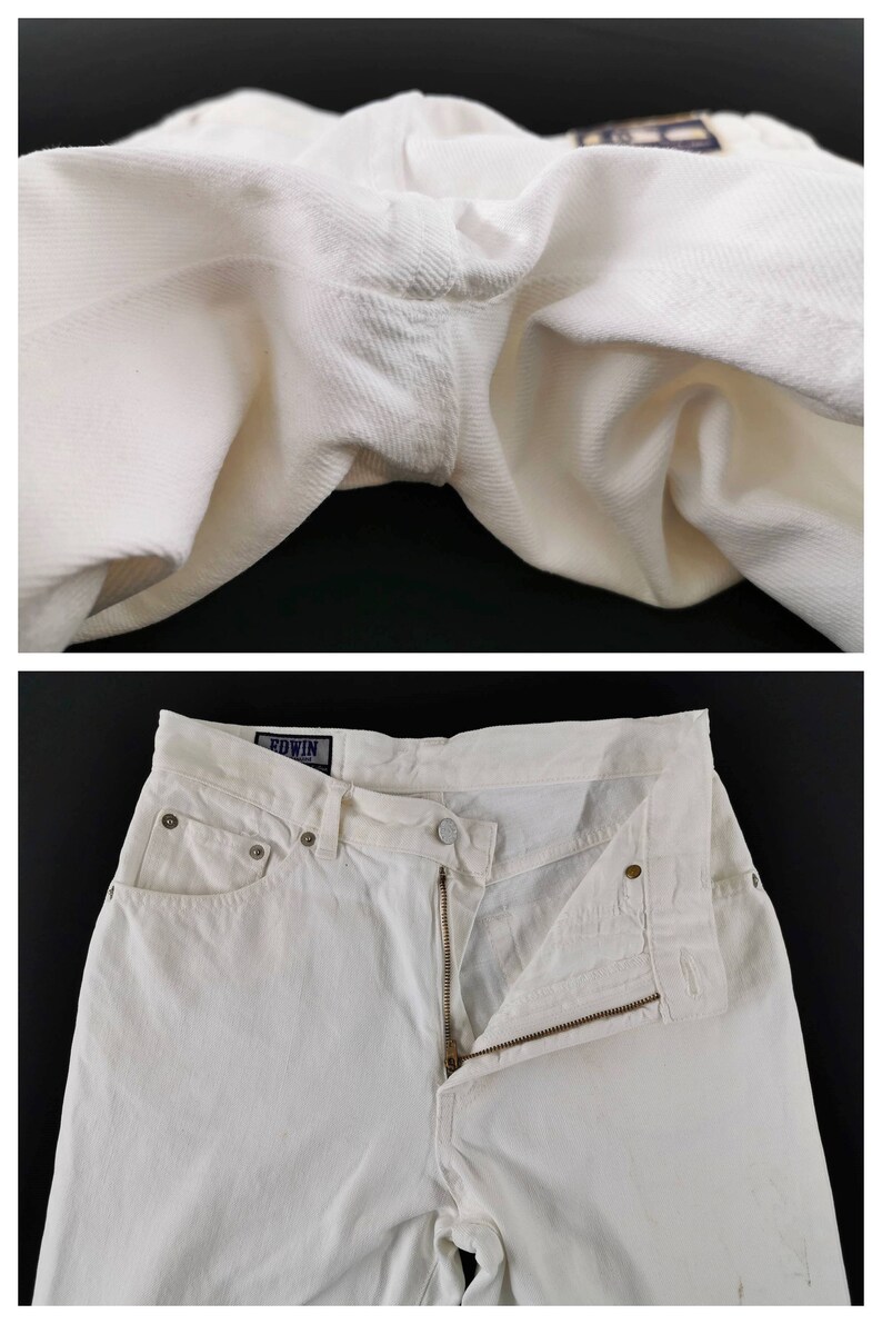 May include: Close-up and full shot of white denim jeans. The jeans have a zipper fly, pockets, and a button closure. The brand name "EDWIN" is visible on a tag. The fabric appears to be a sturdy, textured cotton.