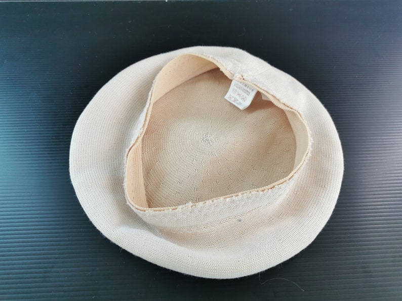 Puede incluir: Un sombrero beige tejido con una corona redonda y un ala ancha. El interior presenta una banda de color m&aacute;s claro y una etiqueta. El sombrero se ve desde el interior, mostrando la textura del tejido.