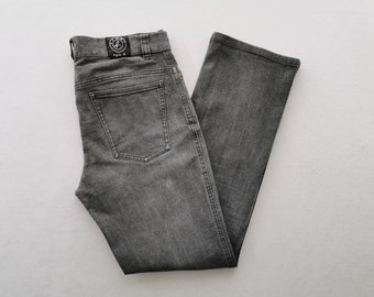 Puede incluir: Unos vaqueros de mezclilla en color gris carbón con corte de pierna recta, diseño clásico de cinco bolsillos y una etiqueta de cuero negro en la cintura trasera con el logotipo circular SPORT b. agnès b.