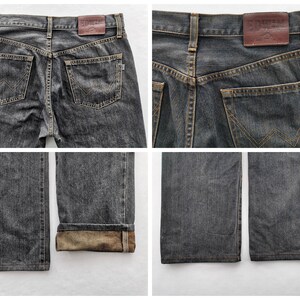 May include: Four-panel image of dark grey denim jeans. The jeans have a classic five-pocket design, with a leather patch on the back waistband. The back pockets feature a distinctive stitched design. The cuffs are folded up, revealing a lighter-coloured interior.
