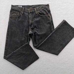 May include: Dark grey denim jeans with a classic five-pocket design. The jeans have a button and zip closure, belt loops, and a straight leg fit. The fabric appears pre-washed for a worn look.