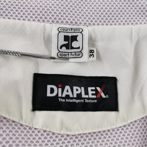 Puede incluir: Primer plano de una tela blanca y rosa claro con una etiqueta que dice "courr&egrave;ges sport futur" y "DiAPLEX The Intelligent Texture". La etiqueta tambi&eacute;n indica una talla 38.